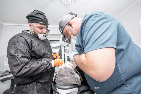 Two dental surgery professionals performing full mouth implant treatment — the qualified clinical team you should expect at a verified UK or Turkey clinic