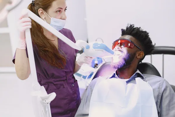 Professional teeth whitening UV light procedure in a dental clinic — professional-grade whitening delivering 4–14 shades improvement